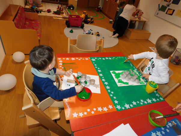 2 Kinder sitzen an einem Tisch. Beide Kinder malen ein Bild