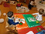 2 Kinder sitzen an einem Tisch. Beide Kinder malen ein Bild