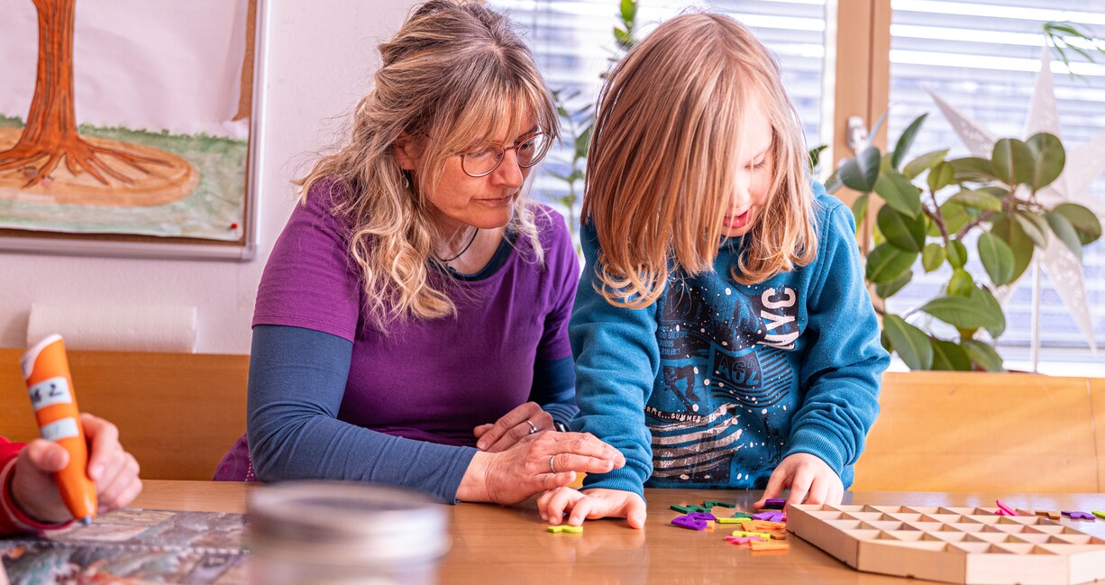 Frau mit Kind am Buchstaben legen