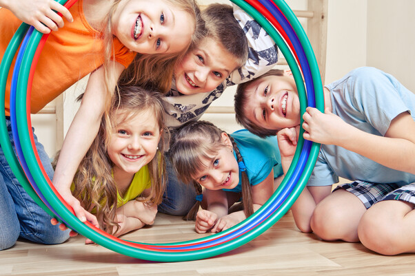 Eine Gruppe Kinder. Sie schauen durch Hullahoop-Reifen. Sie lachen alle.