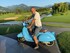 Mann sitzt auf blauem Moped. Er lächelt dabei