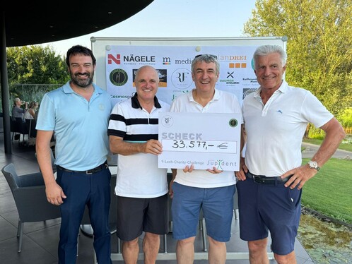 4 Männer, Alle lächeln. Ein Mann hält den Spenden-Check