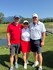 2 Männer und 1 Frau auf dem Golfplatz. Sie lächeln alle.