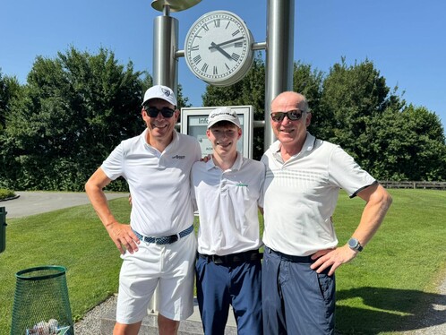 3 Männer auf dem Golfplatz. Sie lächeln alle. 