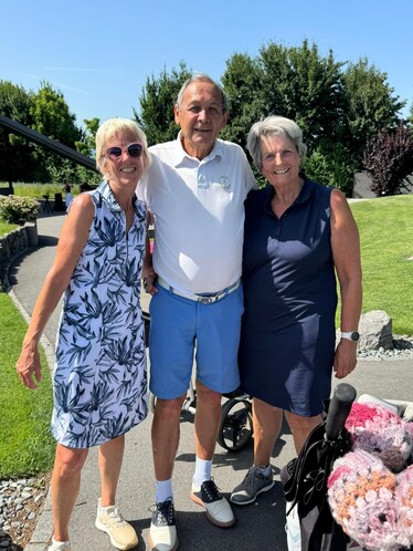 2 Frauen und 1 Mann auf dem Golfplatz. Alle lächeln.