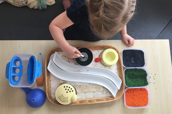 Kind von oben Fotografiert, mit besonderen Spielmaterialien beschäftigt