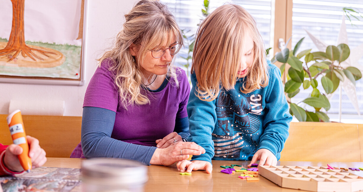 Frau mit Kind am Tisch in ein Spiel vertieft
