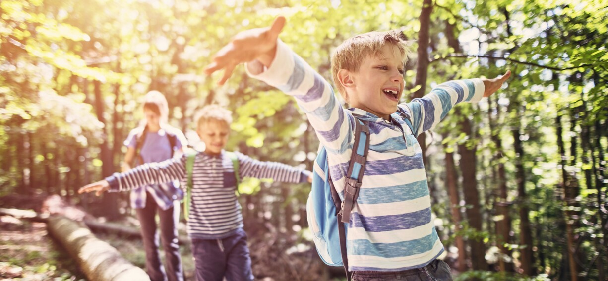 3 Kinder balancieren auf einem Baumstamm