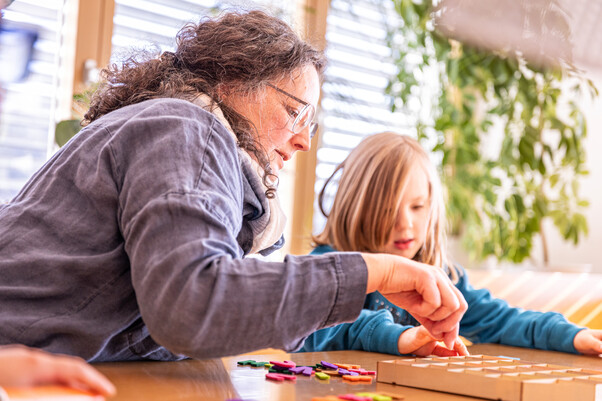 Frau mit Kind am Tisch in ein Spiel vertieft
