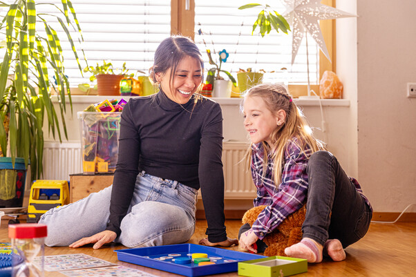 Frau mit Mädchen am Boden, sie spielen und lachen