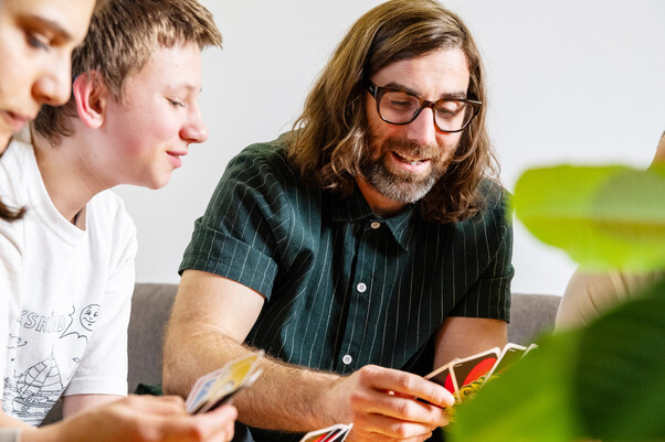 Mann mit 2 Jugendlichen beim UNO-spielen