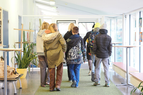 Eine Gruppe von Jugendlichen beim Verlassen des Schulgebäudes von hinten fotografiert 