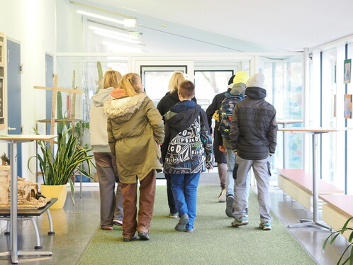 6 Jugendliche von hinten fotografiert, wie sie das Schulgebäude verlassen